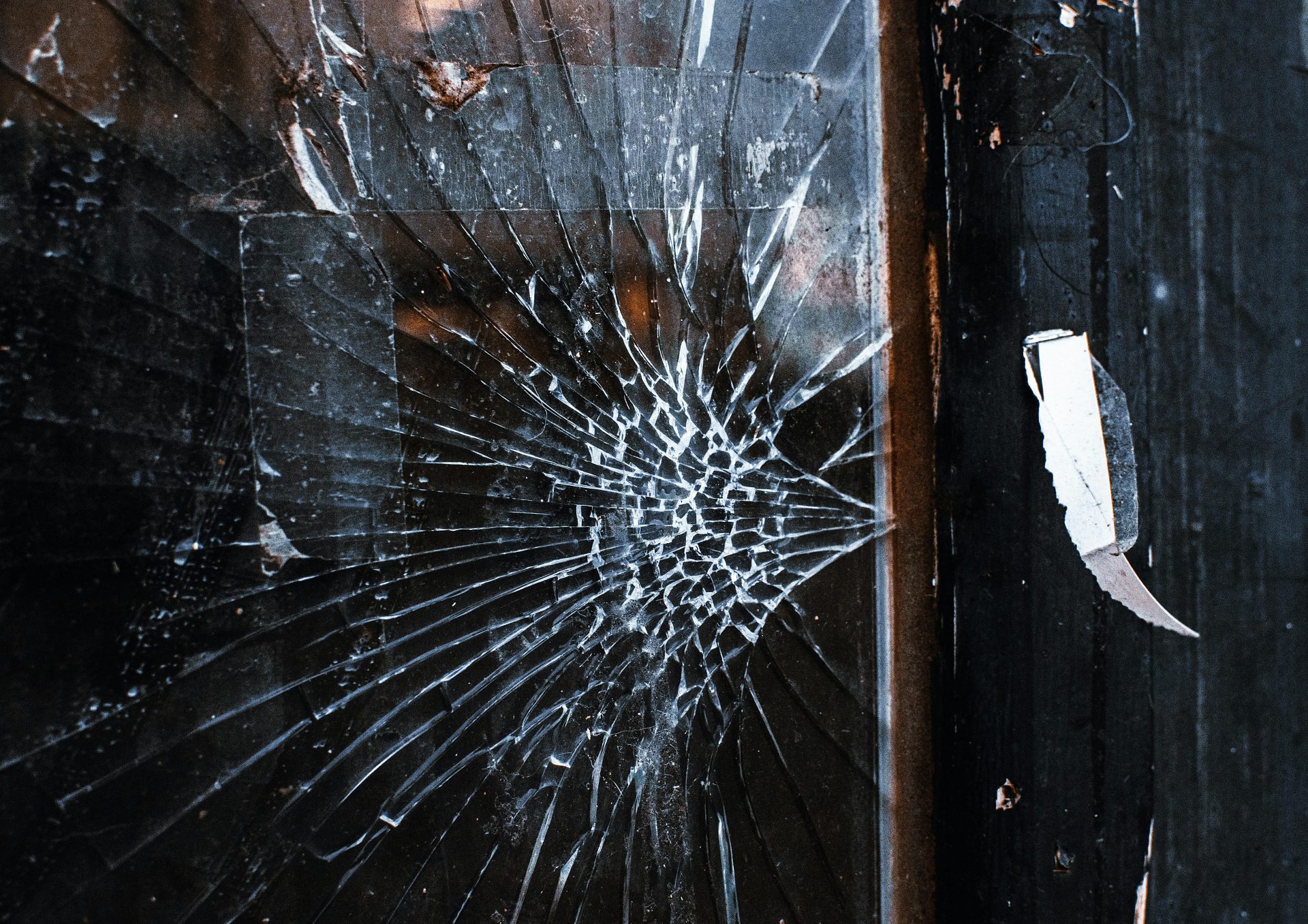 Close-up of a cracked window with a weathered wooden frame and grunge texture.